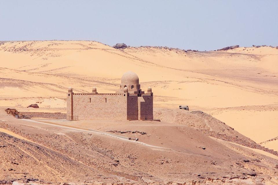 The Aga Khan Mausoleum, a large sand-colored building with a small dome on a low tower, in Aswan, Egypt