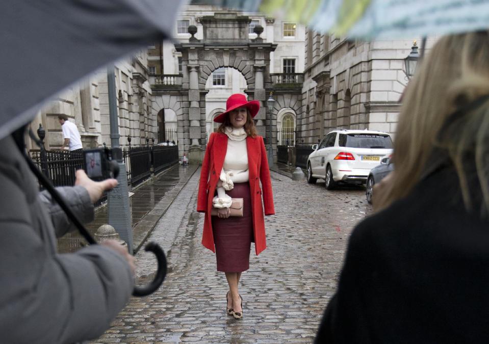 Carmen Negoita a fashion blogger poses for photographs between media umbrellas as rain falls on the first day of London Fashion Week, in London, Friday, Feb. 14, 2014. (AP Photo/Alastair Grant)