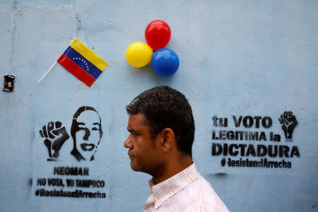A man walks in front of graffiti that reads "Neomar does not vote, neither do I" and "Your vote legitimizes the dictatorship", referring to Neomar Lander, who died during confrontations with security forces, during a nationwide election for new governors in Caracas, Venezuela, October 15, 2017. REUTERS/Carlos Garcia Rawlins