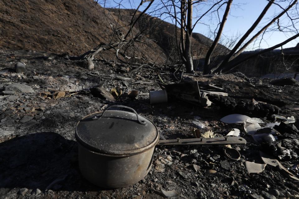 Amid scorched debris, a cooking pot sits in the foreground