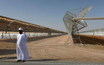 An Emarati stands in front of rows of parabolic shaped mirrors at the Shams 1, Concentrated Solar power (CSP) plant, in al-Gharibiyah district on the outskirts of Abu Dhabi, on March 17, 2013 during the inauguration of the facility. (Photo credit: MARWAN NAAMANI/AFP/Getty Images)