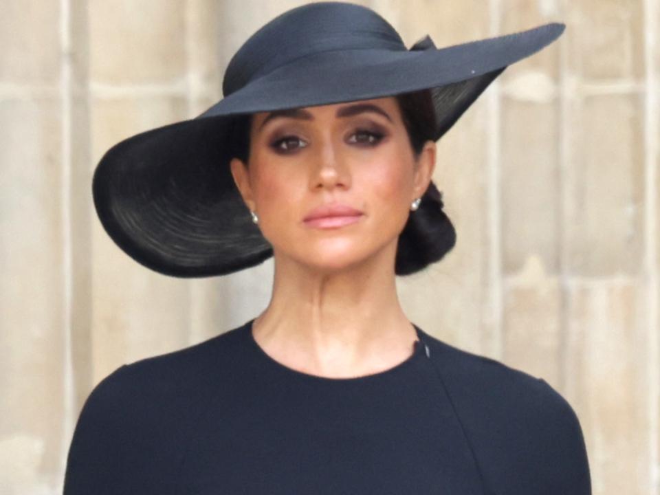 Meghan Markle in a black top and hat