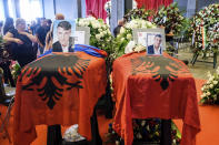 The coffins of Edi Bokrina and Marius Djerri, left, are draped with the Albanian flag prior to the funeral service of some of the victims of a collapsed highway bridge, in Genoa, Italy, Saturday, Aug. 18, 2018. Saturday has been declared a national day of mourning in Italy and includes a state funeral at the industrial port city's fair grounds for those who plunged to their deaths as the 45-meter (150-foot) tall Morandi Bridge gave way Tuesday. (AP Photo/Nicola Marfisi)