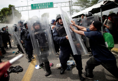 A Honduran migrant, part of a caravan trying to reach the U.S., hits the shield of a federal policeman after storming the Guatemalan checkpoint to enter Mexico, in Ciudad Hidalgo, Mexico October 19, 2018. REUTERS/Ueslei Marcelino