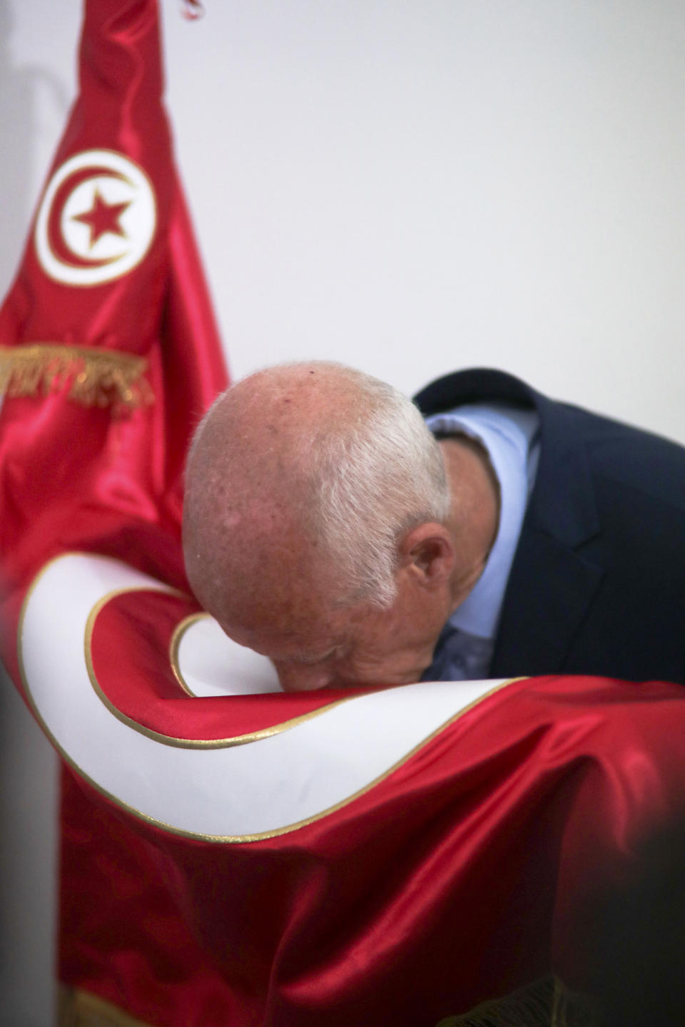 Tunisian former conservative constitutional law professor Kais Saied kisses the national flag in his office in Tunis, Tunisia, Tuesday, Sept. 17, 2019. With more than half the votes in Tunisia's presidential race counted, Kais Saied was in the lead. Media magnate Nabil Karoui, a more modernizing candidate, was in second place with 15.5%. (AP Photo/Mosa'ab Elshamy)