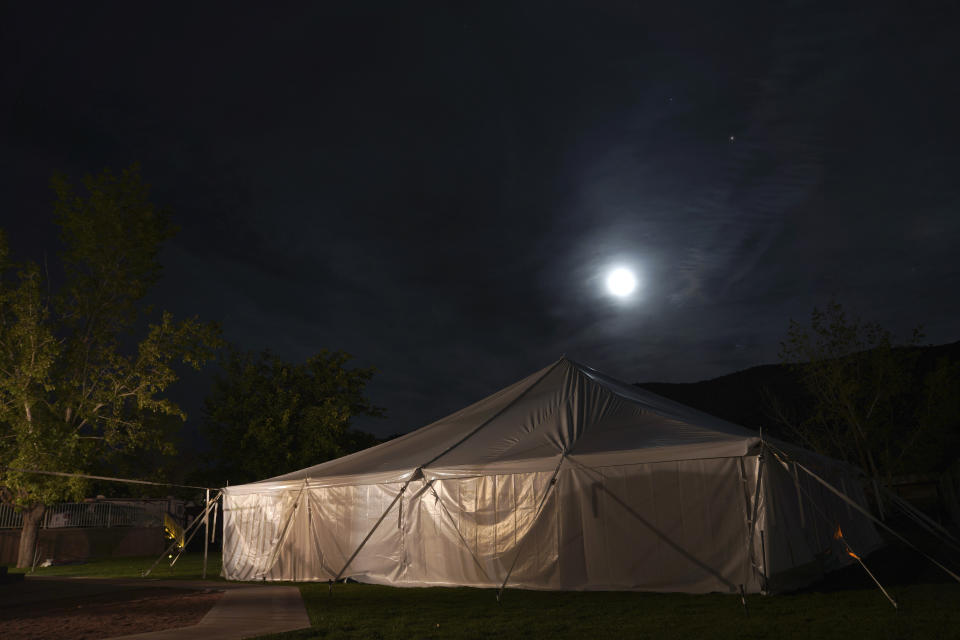 The moon shines over a large tent housing about two dozen individuals partaking in an ayahuasca ceremony, on Sunday, Oct. 16, 2022, in Hildale, Utah. Hummingbird Church, which hosted the weekend ayahuasca retreat, is part of a growing global trend in which people are turning to ayahuasca to treat an array of health problems after conventional medications and therapy failed them. (AP Photo/Jessie Wardarski)