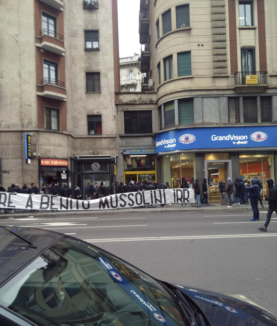 In this photo taken on April 24, 2019 a banner with writing reading in Italian "Honor to Benito Mussolini" is unfolded by Lazio soccer team fans in Milan. Fascist salutes, long a public taboo, have made their way out of the hooligan sections of soccer stadiums and into city streets, as demonstrated by a couple of dozen of the Roman football squad Lazio’s historically right-wing and fascist ‘’ultra’’ fans on visitors’ turf in Milan. (Antonella LoConsolo via AP)