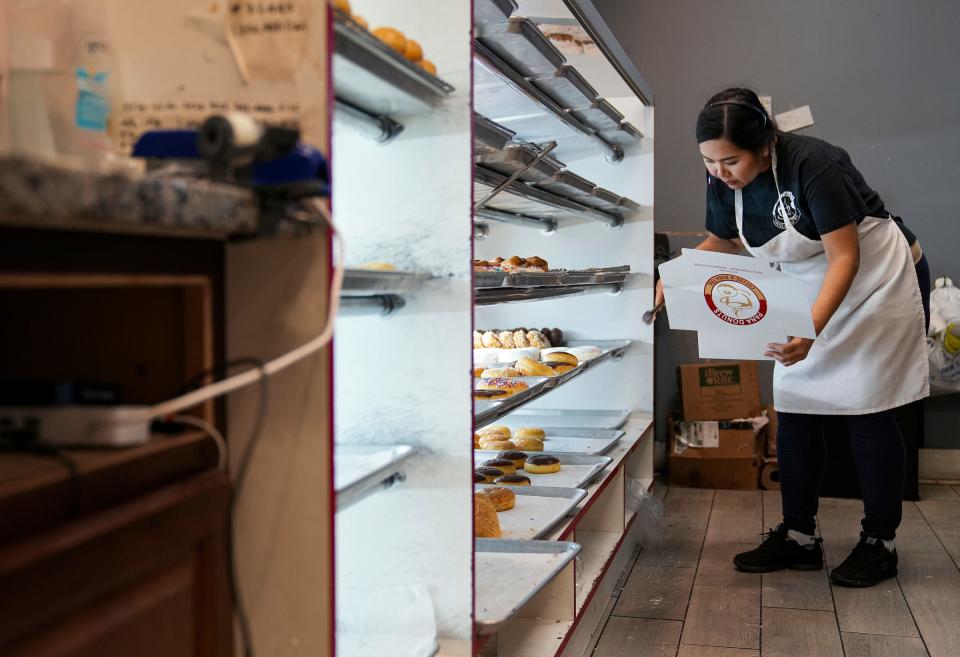 Pichama Prum, who owns PANA Donuts with her husband, Arron Sok, selects doughnuts for a drive-thru customer Thursday, March 23, 2023, at the store's original location on the south side of Indianapolis. 