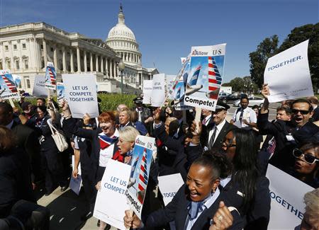 US Airways flight attendants chant during a protest by pilots, flight attendants, baggage handlers and other union members working for American Airlines and US Airways urging the U.S. Justice Department to allow the two companies to merge at a rally in front of the U.S. Capitol building in Washington September 18, 2013. REUTERS/Jim Bourg