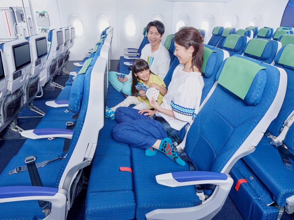 A promotional-style image of a family sitting on a COUCHii aboard an All Nippon Airlines flight