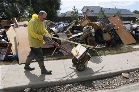 Mark Brothe wheels out more possessions damaged by a flood to add to a pile in front of his house, in Evans, Colorado September 23, 2013. REUTERS/Rick Wilking