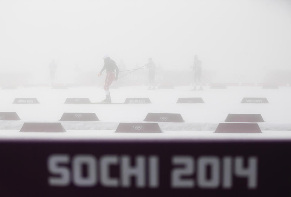 Athletes warm up in thick fog prior to the men's biathlon 15k mass start, at the 2014 Winter Olympics, Monday, Feb. 17, 2014, in Krasnaya Polyana, Russia. The men’s 15-kilometer mass-start biathlon race at the Sochi Olympics has been delayed for an indefinite time due to fog, one day after the event had been called off for the same reason. (AP Photo/Gero Breloer)