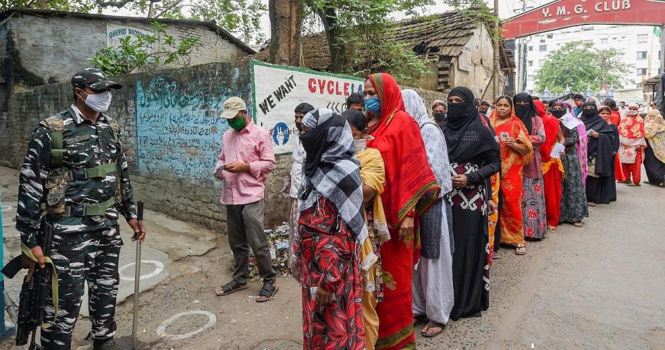 People stand in a queue to cast their vote at a polling station during the 6th phase of State Assembly Election at Birati, in North 24 Parganas.