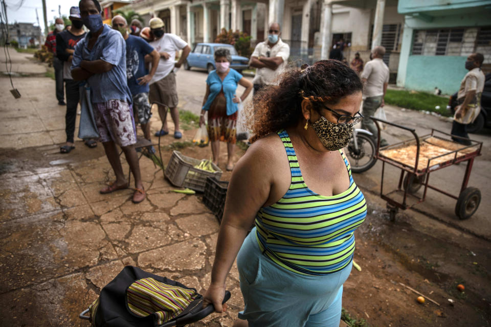 Yuliet Colon pulls her rolling grocery cart as she walks home after after a visit to the agro market in Havana, Cuba, Friday, April 2, 2021. Colon helps Cubans cope with shortages exacerbated by the new coronavirus pandemic with Facebook posts of culinary creations designed around what is actually available at the market. (AP Photo/Ramon Espinosa)