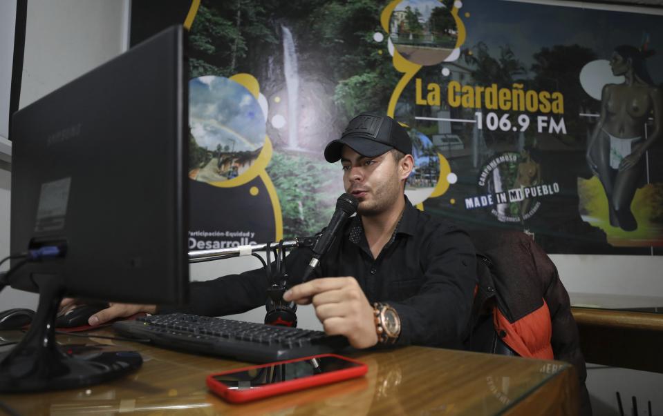 Radio jockey Cristian Sanchez makes a COVID-19 public safety announcement on the local radio station in Campohermoso, Colombia, Thursday, March 18, 2021. According to the town mayor, the key to Campohermoso being able to stay COVID free is a continuous barrage of public service announcements on the radio and public announcement systems teaching people how to stay safe during the pandemic. (AP Photo/Fernando Vergara)