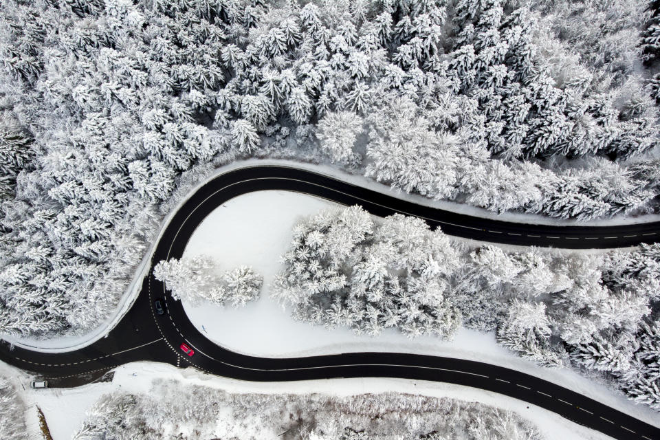 Cars drive on the road of the "Col du Mollendruz" among snow-covered trees in a forest after snowfall, in the Jura Mountains, in Mont-la-Ville, Switzerland, Sunday, Dec. 6, 2020. (Laurent Gillieron/Keystone via AP)