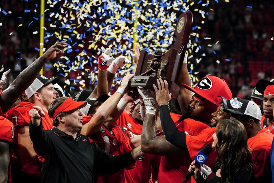 Georgia head coach Kirby Smart and defensive lineman Jalen Carter (88) hoist the trophy after defeating LSU in the SEC Championship game.