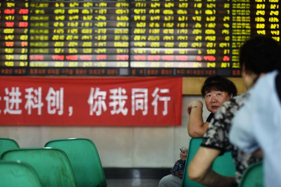 Stock investors chat beside a banner promoting the newly launched STAR market in a brokerage house in Hangzhou in east China's Zhejiang province Monday, July 22, 2019, the trading day of the new board. (Chinatopix via AP)