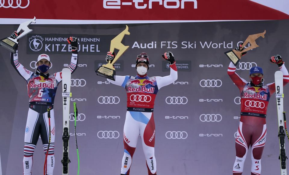 Switzerland's Beat Feuz, center, winner of an alpine ski, men's World Cup downhill, celebrates on the podium with second-placed France's Johan Clarey, left, and third-placed Austria's Matthias Mayer, in Kitzbuehel, Austria, Sunday, Jan. 24, 2021. (AP Photo/Giovanni Auletta)