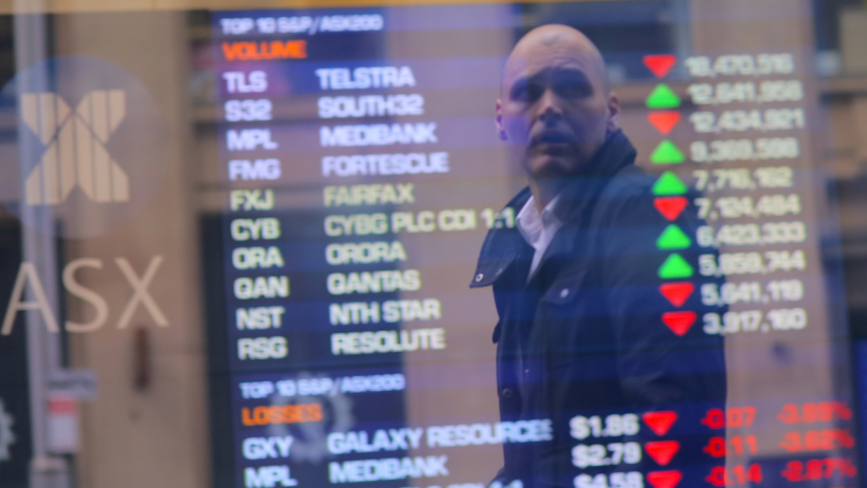 Man looking at ASX stock prices with a worried look on his face.