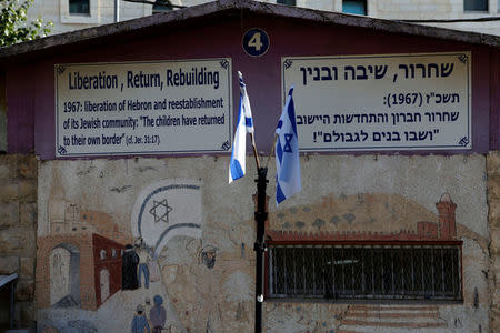 Israeli flags and signs are seen at a military camp in the West Bank city of Hebron October 17, 2017. REUTERS/Mussa Qawasma