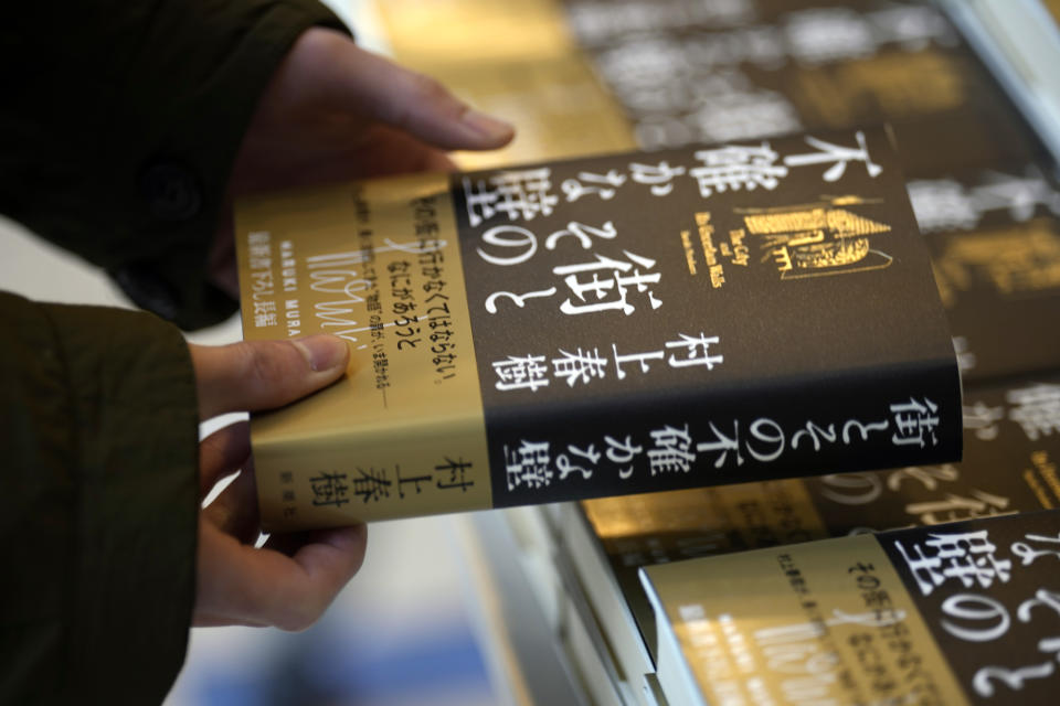 A customer picks up Japanese writer Haruki Murakami's new novel "The City and Its Uncertain Walls" on the first day for sale at Kinokuniya bookstore in Shinjuku district on early Thursday, April 13, 2023, in Tokyo. Murakami wrote a story of a walled city when he was fresh off his debut. More than four decades later, as a seasoned and acclaimed novelist, he gave it a new life as “The City and Its Uncertain Walls.”(AP Photo/Eugene Hoshiko)