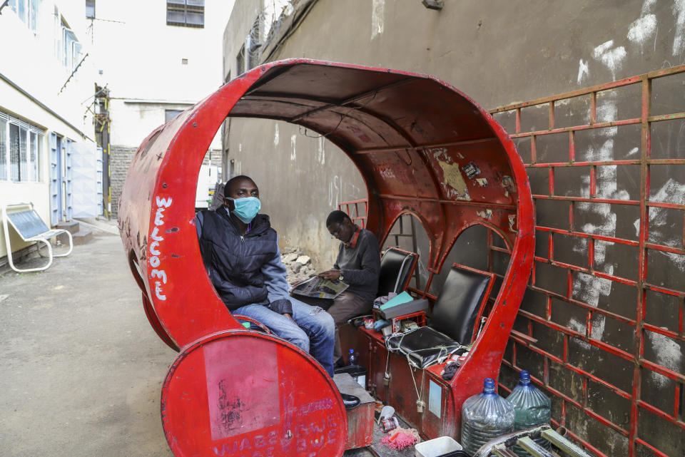 Francis Kimani Waweru sits in his shoeshine stall, which he complains has seen few customers since fears of the new coronavirus took hold, on a street in downtown Nairobi, Kenya Friday, March 20, 2020. For most people, the new coronavirus causes only mild or moderate symptoms such as fever and cough and the vast majority recover in 2-6 weeks but for some, especially older adults and people with existing health issues, the virus that causes COVID-19 can result in more severe illness, including pneumonia. (AP Photo/Patrick Ngugi)
