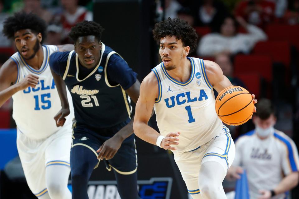 UCLA guard Jules Bernard (1) drives with the ball as Akron center Aziz Bandaogo (21) and UCLA center Myles Johnson (15) pursue during the first half of a first-round NCAA college basketball tournament game, Thursday, March 17, 2022, in Portland, Ore. (AP Photo/Craig Mitchelldyer)