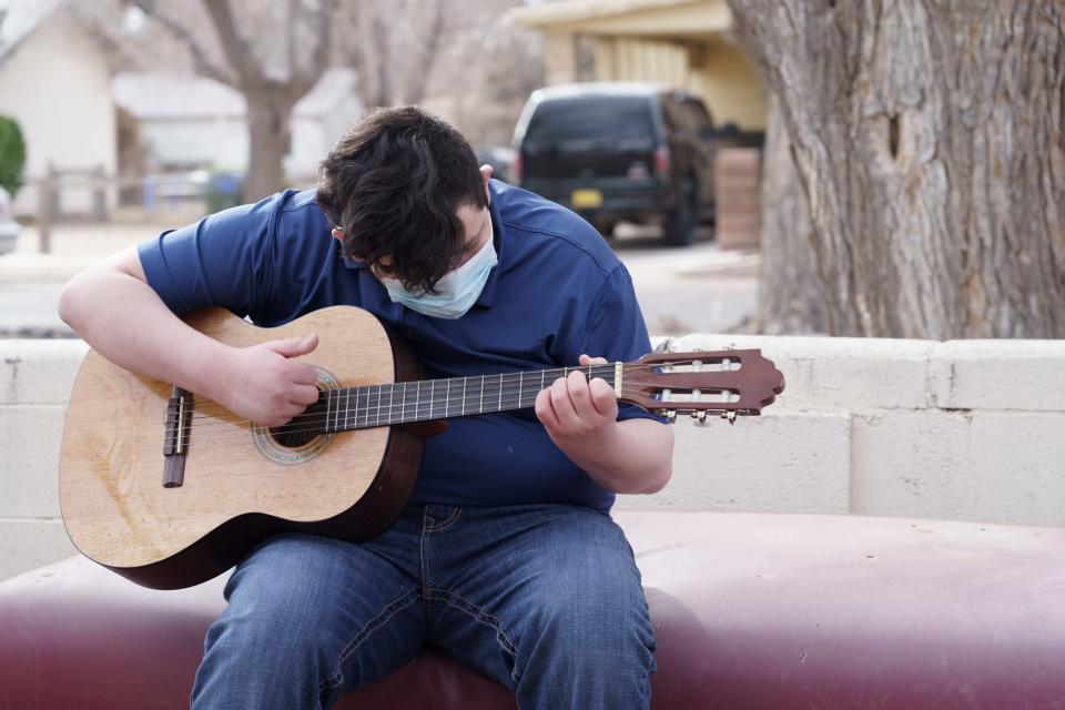 Alan strums his guitar outside of his house in Deming, New Mexico, on February 13, 2021. Alan, who has Tourette Syndrome, has struggled with teachers and peers at school because of his involuntary outbursts.