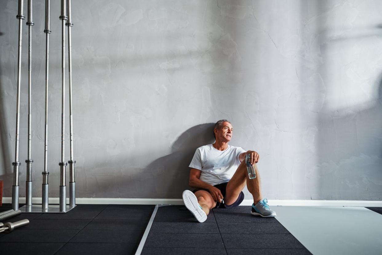 Senior man drinking water and resting after a gym workout