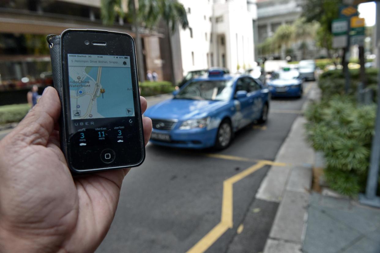 A pedestrian uses the Uber app in the financial district of Singapore. (PHOTO: AFP)