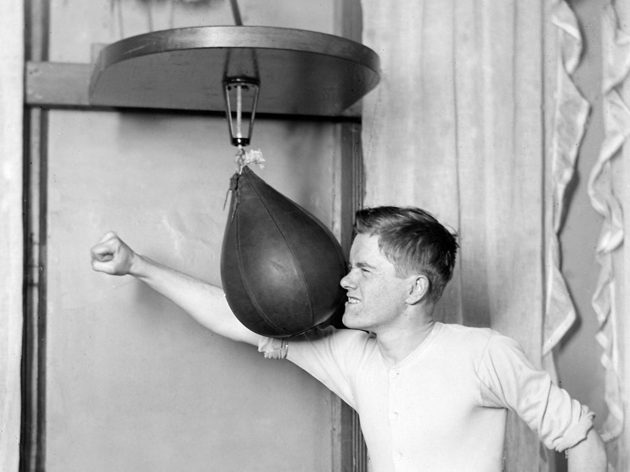 A young man misses a punching bag in 1910.