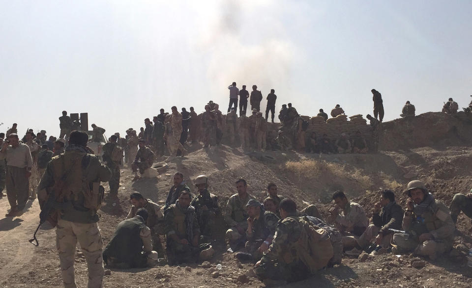 Peshmerga soldiers wait and watch behind fortified position while exlosion goes off down the road. (Photo: Ash Gallagher for Yahoo News)