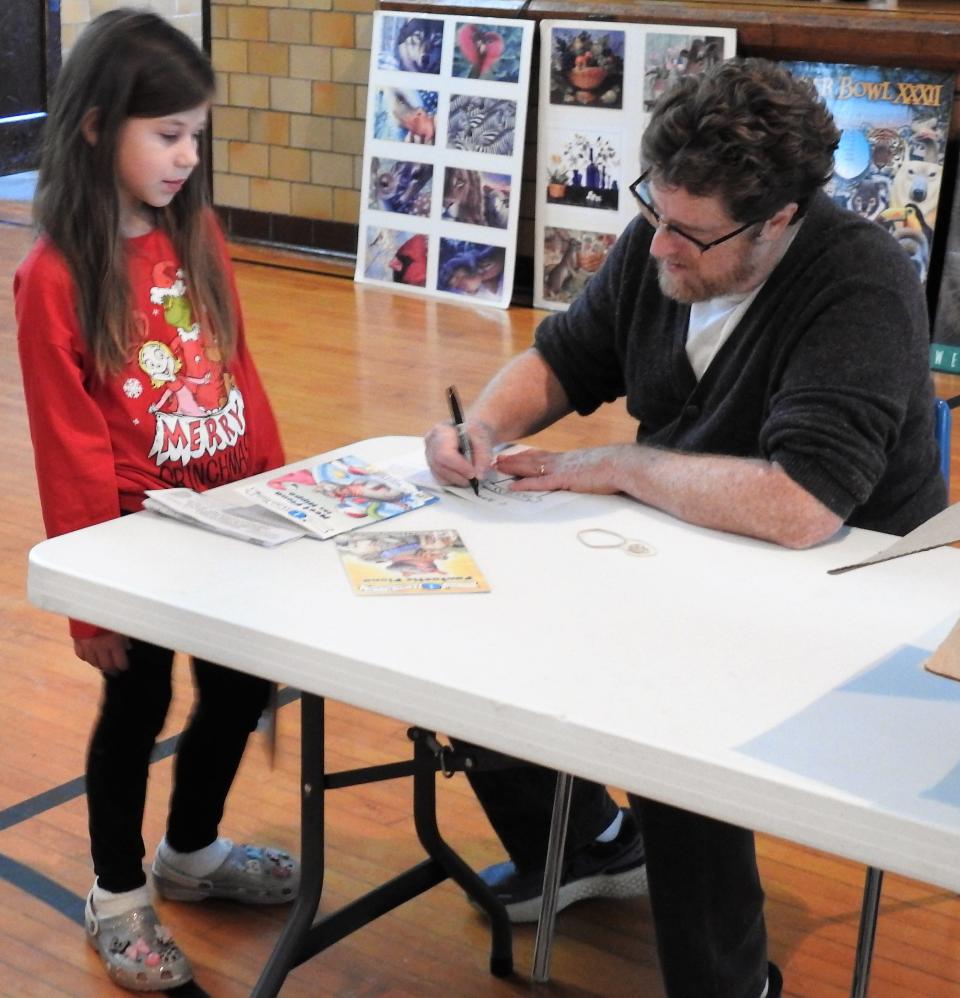 Children's book illustrator and author Richard Cowdrey autographs a book for second-grader Aidyn Blair. Cowdrey on Wednesday had a presentation for students at Conesville Elementary School and signed for kids who had books pre-ordered.