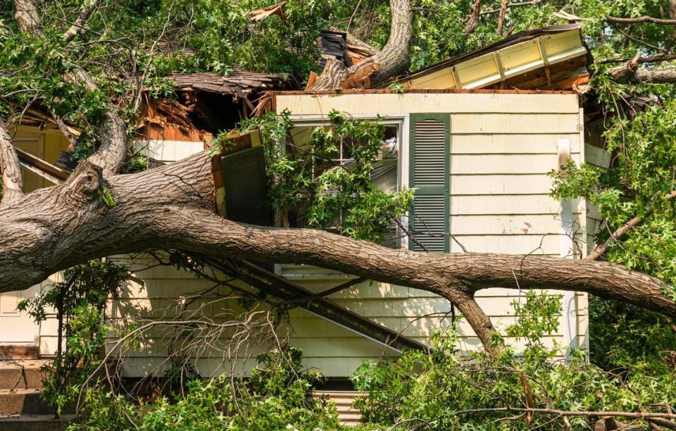 A tree rests on the roof of a house Saturday, July 14, 2023, in Prairie Village where it landed after being blown over by a strong storm on Friday. Damage from Friday night’s storm caused mass power outages throughout the Kansas City Metro area.