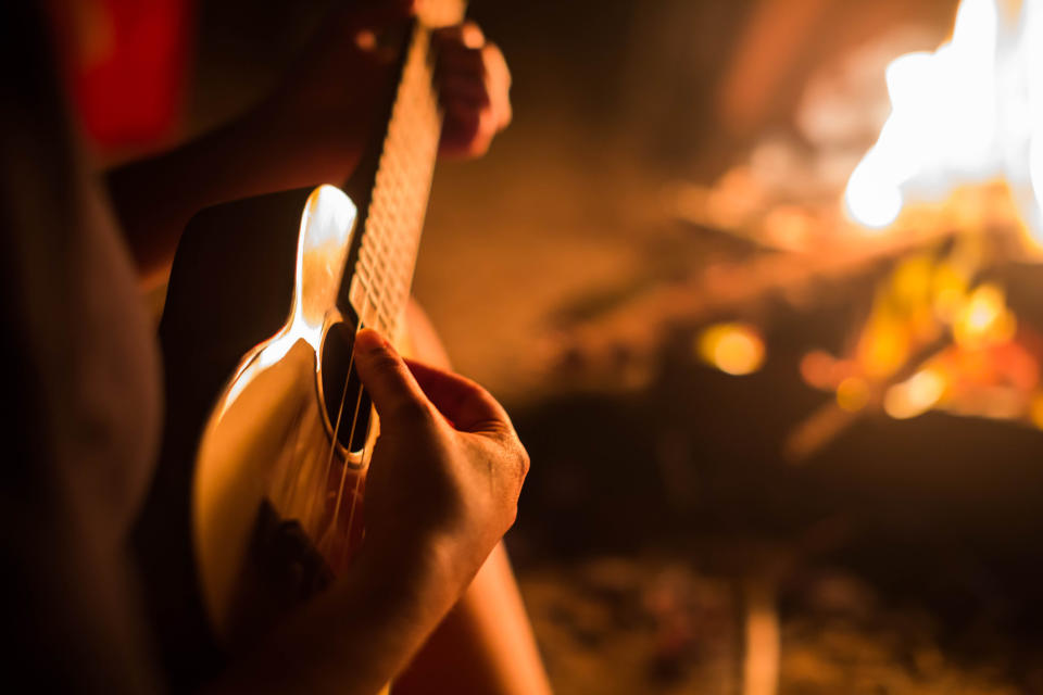 Someone playing guitar by a campfire