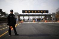 A South Korean security guard stands guard on an empty road which leads to the Kaesong Industrial Complex (KIC) at the South's CIQ (Customs, Immigration and Quarantine), just south of the demilitarised zone separating the two Koreas, in Paju, South Korea, February 11, 2016. The Korean characters on the gateway reads "Inter-Korean Transit Office". REUTERS/Kim Hong-Ji