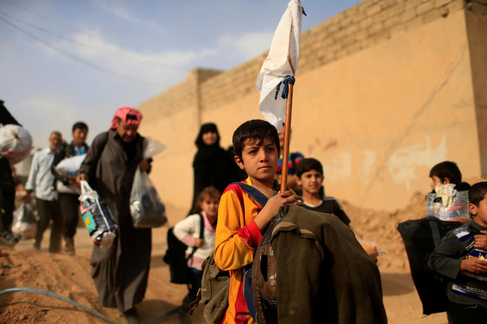 A displaced Iraqi boy holds up a white flag while fleeing Samah neighborhood