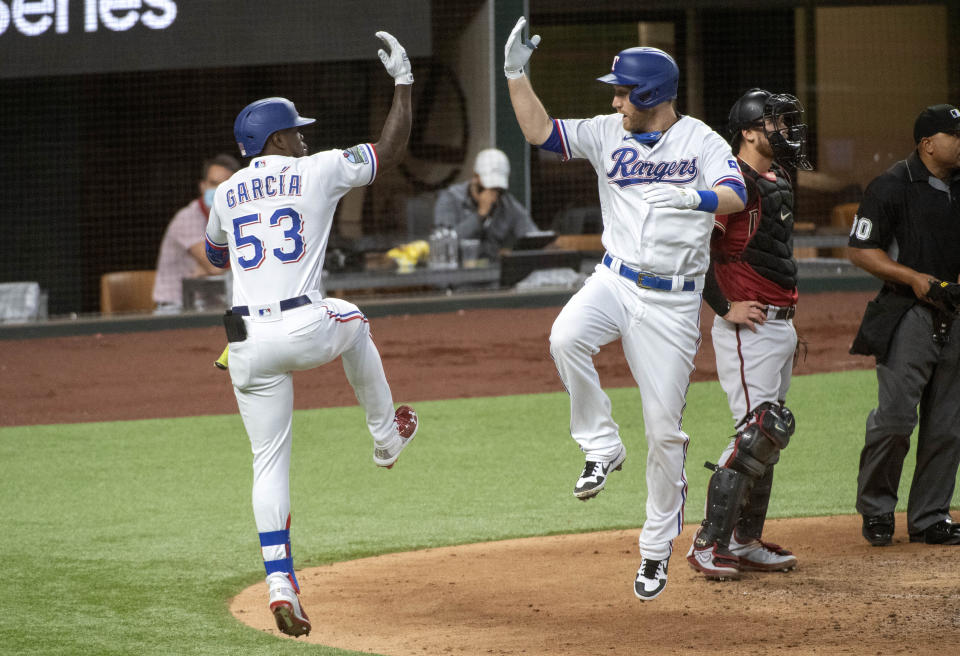 Texas Rangers' Todd Frazier celebrates his solo home run off of Arizona Diamondbacks starting pitcher Madison Bumgarner with Adolis Garcia (53) as catcher Carson Kelly stands by during the fourth inning of a baseball game Wednesday, July 29, 2020, in Arlington, Texas. (AP Photo/Jeffrey McWhorter)