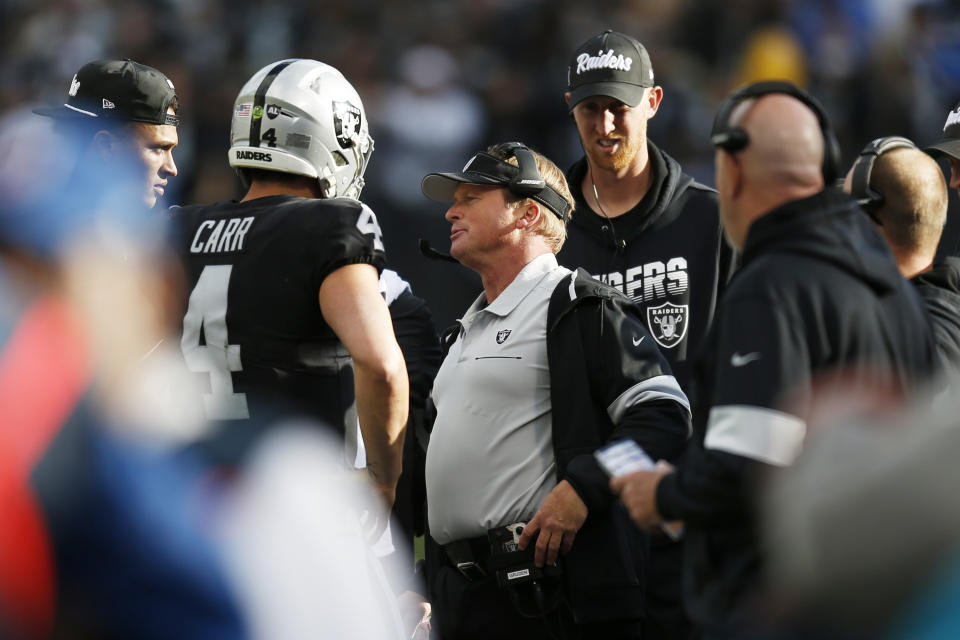 Oakland Raiders head coach Jon Gruden, center, talks with quarterback Derek Carr (4) during the second half of an NFL football game against the Jacksonville Jaguars in Oakland, Calif., Sunday, Dec. 15, 2019. (AP Photo/D. Ross Cameron)