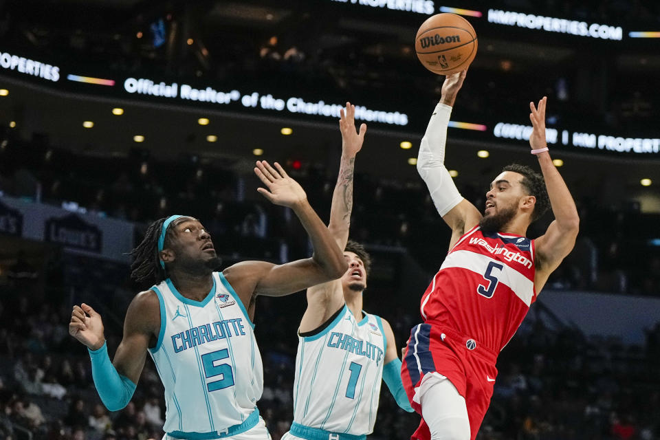 Washington Wizards guard Tyus Jones shoots over Charlotte Hornets center Mark Williams, left, and guard LaMelo Ball during the first half of an NBA basketball game on Wednesday, Nov. 22, 2023, in Charlotte, N.C. (AP Photo/Chris Carlson)