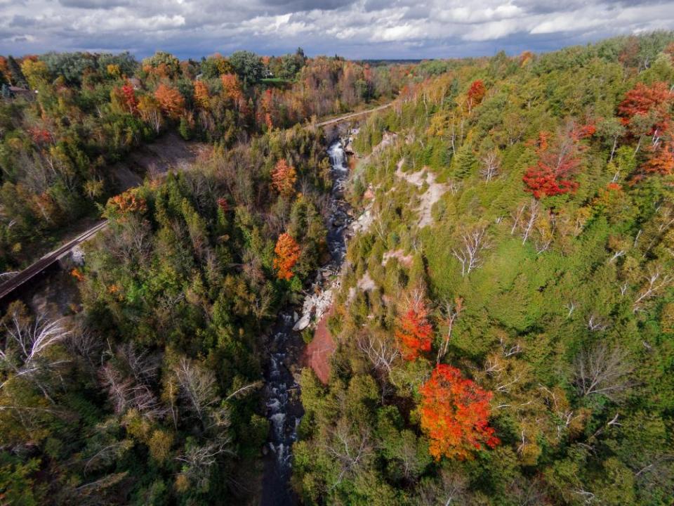 Autumn colours dot the steep valley walls of the Port Credit River and Cataract Falls in the Forks of The Credit Provincial Park.