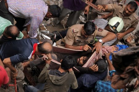 Rescue workers carry a man who was rescued from the rubble at the site of a collapsed building in Mumbai