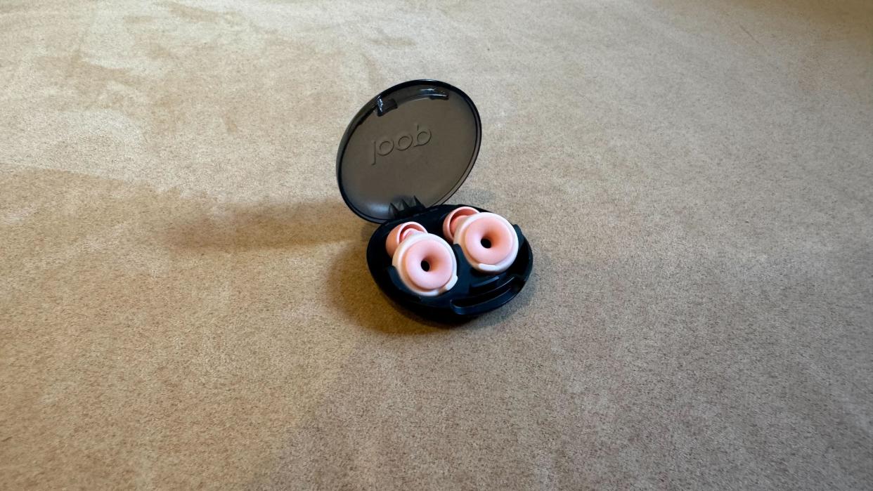  Loop Switch earbuds on a pink surface in the case with the lid open. 