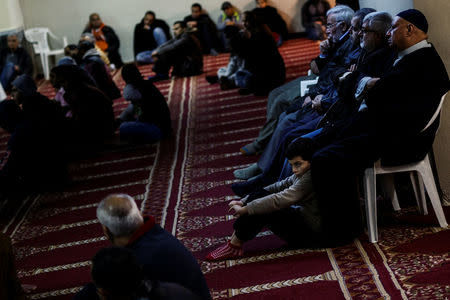 A boy sits next to his father as muslims living in Greece attend Friday prayers at the Masjid Al-Salam makeshift mosque in Athens, Greece, February 3, 2017. REUTERS/Alkis Konstantinidis