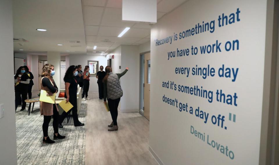 A tour group passes by a quote from Demi Lovato that's affixed to a wall at a drug recovery center.