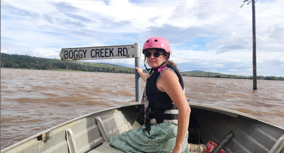 A woman holding onto a street sign while inside a small boat. 