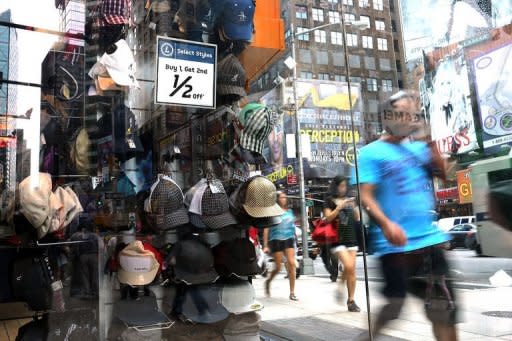 People walk by a store advertising a sale on hats in Times Square in New York City. Weak consumer spending stunted US growth in the last quarter, data showed Friday, leaving the race for the White House wide open and putting discussion about more economic stimulus firmly on the Fed's agenda