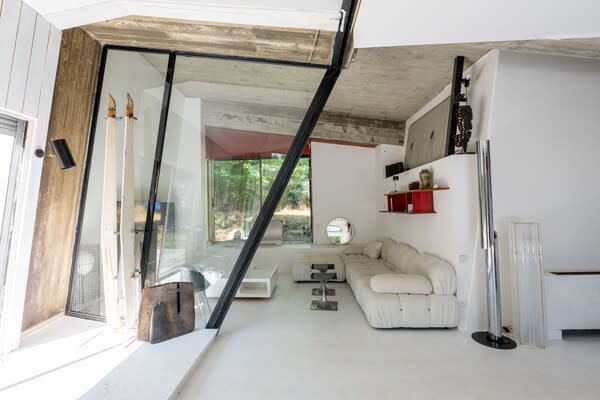 A sloping glass wall serves as a separation between the two living spaces on the first floor.