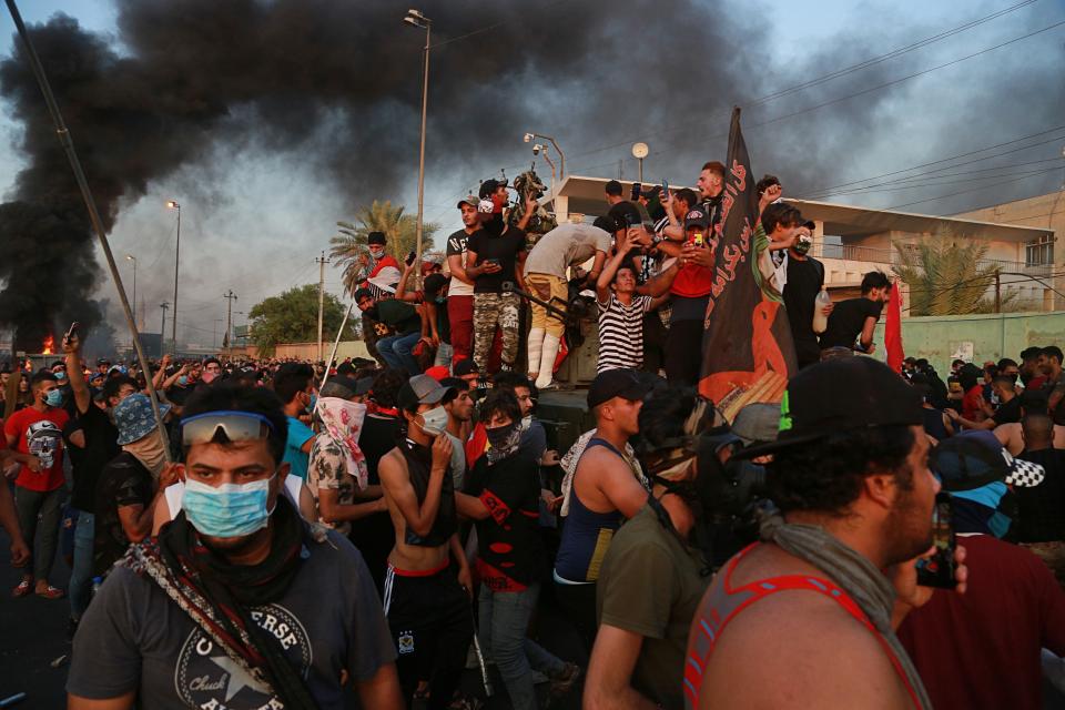 Anti-government protesters take over an armored vehicle, before they burn it during a demonstration in Baghdad, Iraq, Thursday, Oct. 3, 2019. Iraqi security forces fired live bullets into the air and used tear gas against a few hundred protesters in central Baghdad on Thursday, hours after a curfew was announced in the Iraqi capital on the heels of two days of deadly violence that gripped the country amid anti-government protests. (AP Photo/Hadi Mizban)